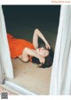 A woman in an orange dress laying on the floor.