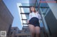 A woman in a skirt and shirt posing in front of a building.