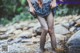 A woman in a plaid skirt is standing in a stream.