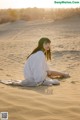 A woman sitting on top of a sandy beach.