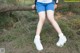 A woman in blue shorts and white sneakers sitting on a tree branch.