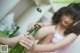 A woman sitting on a bed holding a bottle of beer.