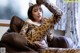 A woman in a leopard print outfit sitting on a brown couch.