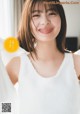 A woman in a white tank top smiles at the camera.