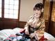 A woman in a kimono sitting on a bed.