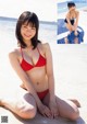 A woman in a red bikini sitting on the beach.